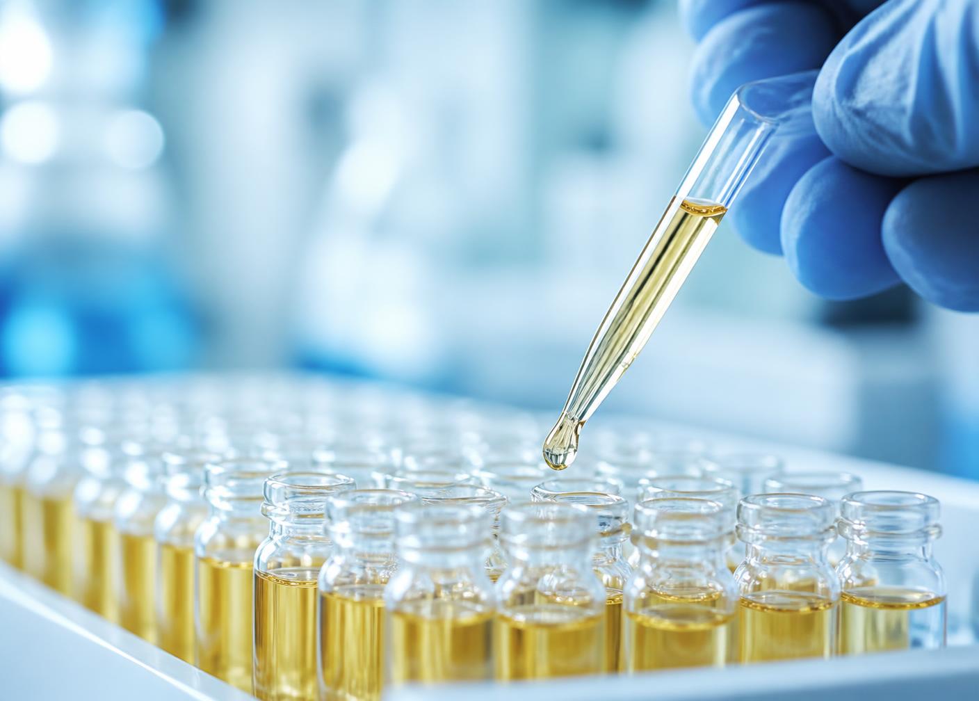 Technician pipetting serum into glass vials during preparation
